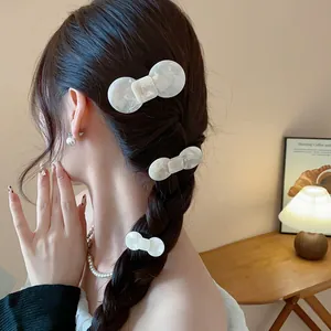 Detailed view of elegant white resin bow hair clips with marble texture on braided hair