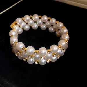 Close-up of elegant three-layer wrap bracelet with white pearls and sparkling rhinestones