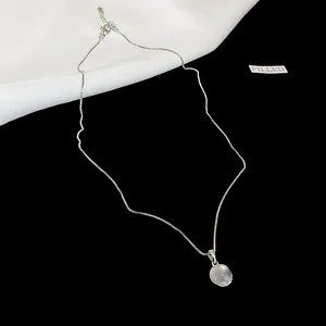 Close-up of minimalist silver necklace featuring a round translucent resin pendant