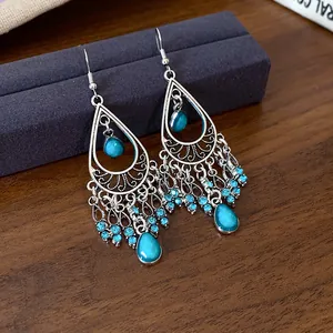 Close-up detail of bohemian silver-tone teardrop earrings with blue rhinestone tassels
