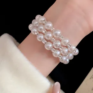 Detailed macro view of an elegant triple-layer pearl bracelet with sparkling rhinestones