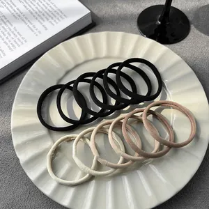 Minimalist high elasticity hair ties in black and neutral beige tones on a ceramic plate