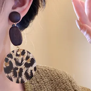 Close-up of stylish leopard print wooden pendant earrings on a female model's ear
