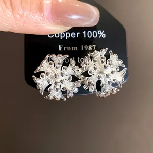 Detailed view of elegant silver-toned flower cluster earrings on a black display card