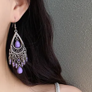Close-up of Bohemian vintage teardrop tassel earrings with purple stones on an Asian model
