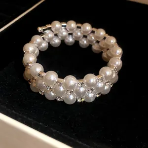 Detailed macro shot of three-layer pearl bracelet with sparkling rhinestone accents.