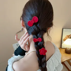 Back view of a woman wearing three red resin flower and bow hair clips in a braid