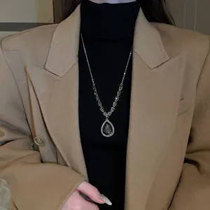 Gros plan d'un collier avec pendentif en zircone poire porté sur un col roulé noir.