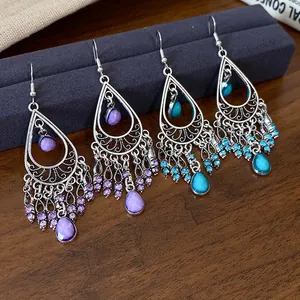 Detail view of bohemian teardrop tassel earrings with purple and turquoise stones.