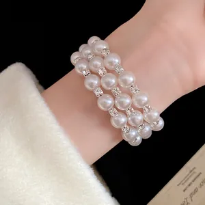 Detailed view of a triple-layer pearl bracelet with rhinestone spacers on a model's wrist