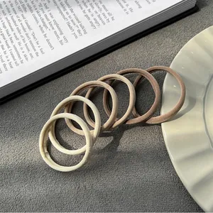 Detail shot of high-elastic hair ties in neutral earthy tones on a gray textured surface