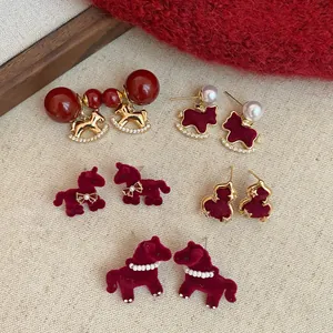 Vue détaillée de boucles d'oreilles cheval en velours rouge et plaqué or avec perles.