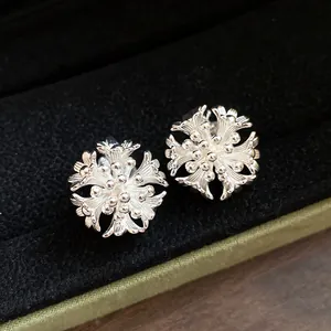 Detailed close-up of intricate silver flower cluster clip-on earrings on black velvet