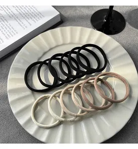 Close-up of minimalist high-elasticity hair ties in neutral colors on a white plate