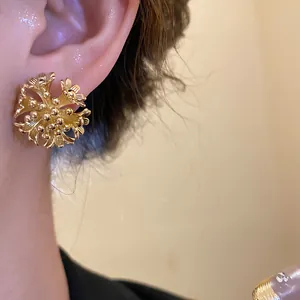 Detail of 18k gold plated flower cluster stud earrings worn on a model's ear