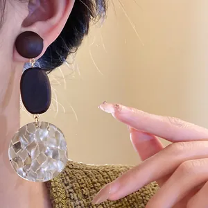 Detailed macro shot of vintage wooden dangling earrings with textured shell mosaic disk
