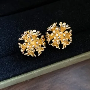 Detailed macro view of 18k gold plated flower cluster ear clips on a black velvet display
