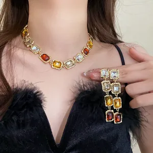 Detail view of a luxury vintage square gemstone necklace and long earring set on a model