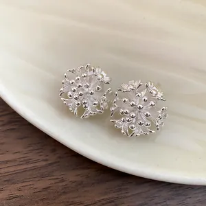 Close-up of intricate silver-tone flower cluster clip-on earrings on a shell tray