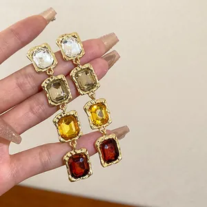 Detailed close-up of long dangling earrings with colorful rectangular faceted crystals.
