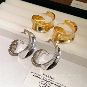 Stylish modern wide curved metal hoop earrings in polished gold and silver finishes