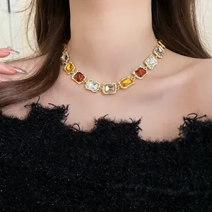 Close-up of vintage gold necklace with square amber and clear gemstones on model neck.