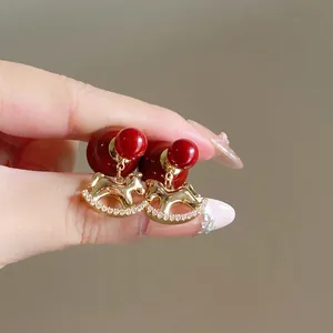 Vue détaillée des boucles d'oreilles cheval à bascule avec perles et zircons rouges