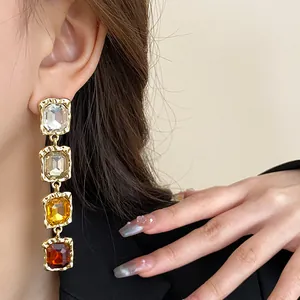 Close-up of elegant long dangle earrings with colorful square gemstones