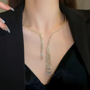 Close-up of elegant zircon tassel necklace on model wearing black velvet dress.