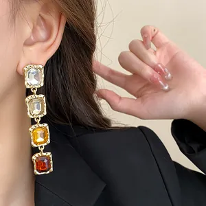 Detail view of elegant drop earrings with four square gradient rhinestones in gold tone
