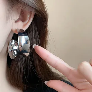 Detail view of oversized wide metallic hoop earrings with a minimalist silver finish