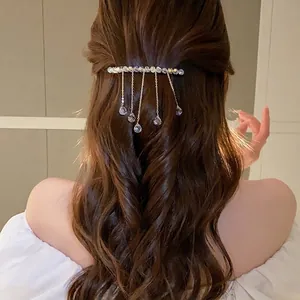 Elegant fashion hair clip with sparkling crystal tassels worn on long wavy brown hair