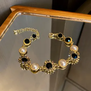 Vue détaillée d'un élégant bracelet en or avec perles, cristaux noirs et strass.