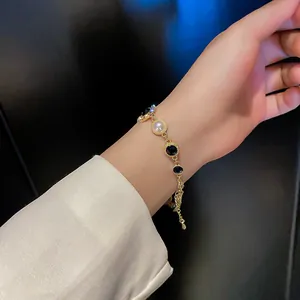 Détail d'un bracelet élégant avec des perles et des pierres précieuses noires au poignet.