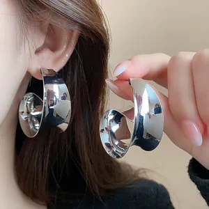 Detailed close-up showing wide metallic silver twisted hoop earrings on a model's ear