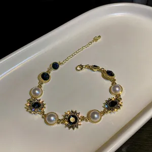 Bracelet doré élégant avec perles blanches et strass bleu marine pour un look chic.
