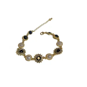 Bracelet élégant doré avec perles blanches et cristaux bleu marine en forme de tournesol