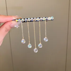 Close-up view of a shimmering crystal tassel hair clip featuring iridescent beads and gold chains