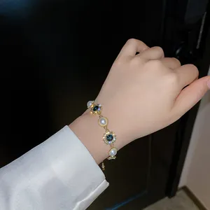 Vue détaillée d'un élégant bracelet en or avec perles et cristaux bleu foncé.