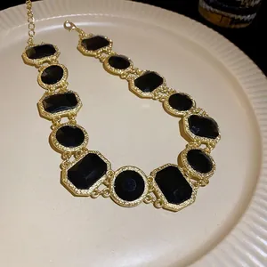 Elegant vintage gold-plated necklace with black square and round gemstones on a plate