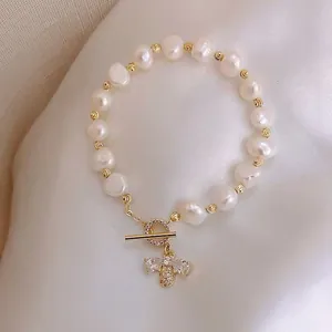 Detailed view of a freshwater pearl bracelet with a pavé-set bee charm and OT clasp