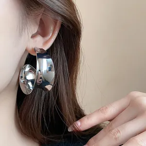 Detail shot of wide-surface silver metallic hoop earring with high-reflective finish