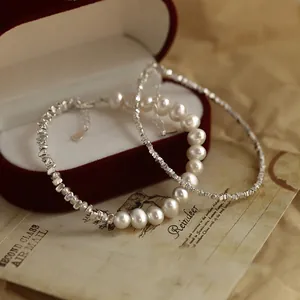 Primo piano di eleganti bracciali con pepite d'argento e perle d'acqua dolce su sfondo vintage