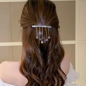 Close-up of elegant crystal tassel hair clip with iridescent teardrop pendants on wavy hair