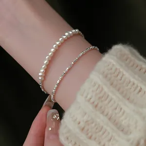 Vista dettagliata di un set di bracciali in argento schiacciato e perle bianche sul polso