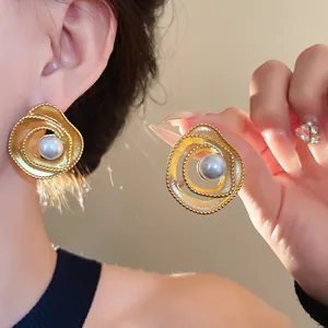 Detail view of vintage gold spiral stud earrings with a lustrous white faux pearl.