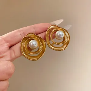 Detailed macro view of vintage gold spiral stud earrings featuring elegant faux pearl centers