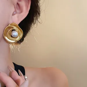 Macro view of vintage gold-tone spiral earrings with a center faux pearl
