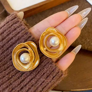 Detailed view of vintage gold spiral stud earrings with elegant faux pearl centers