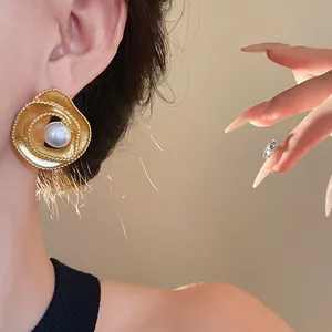 Elegant vintage gold spiral stud earring featuring a large faux pearl detail on model